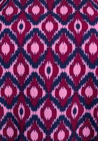 Textil mit einem sich wiederholenden Rautenmuster, in tiefrot, marineblau und sanftem Rosa. Das Material zeigt eine leichte Textur und Tiefe.