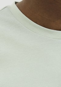 Lichtgroene trui met ronde hals en een gestructureerde stof. De kraag is geribbeld en het materiaal lijkt zacht en ademend.