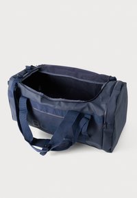 Saco de duffel azul marinho com formato retangular e fecho em zíper. Feito de tecido durável, apresenta duas alças de transporte e um bolso em malha.