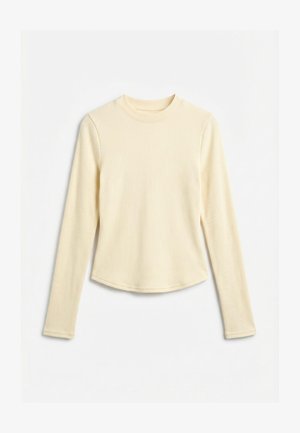 Μπεζ ριμπ μπλούζα με μακριά μανίκια, στρογγυλή λαιμόκοψη και ελαφρώς κυρτή βάση, απλωμένη σε λευκό φόντο.