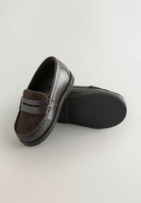 Dunkelbraune Leder- und Velourslederhausschuhe mit gestickten Details und strukturiertem schwarzen Gummisohle, auf einem hellen Hintergrund präsentiert.