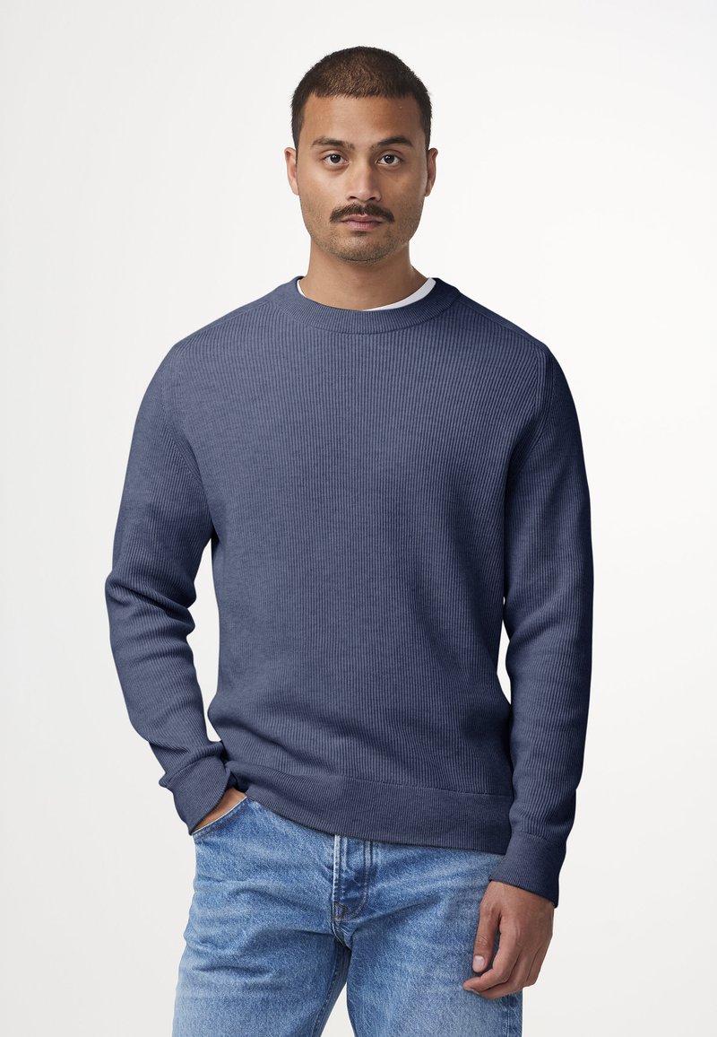 Maglione a coste blu navy con scollatura rotonda e maniche lunghe, abbinato a jeans in denim azzurro. Tessuto morbido, design casual.