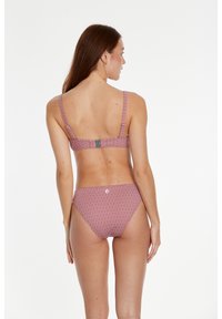 Bikini set s crvenim uzorkom i geometrijskim dizajnom. Ima široke naramenice, kopčanje na leđima i donji deo s niskim strukom. Glatka tekstura tkanine.