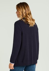 Marineblauer Strickpullover mit langen Ärmeln, gerippten Bündchen und Saum. Glatte Textur mit geradem Rückendesign und legerer Passform.