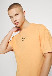 Karl Kani SMALL SIGNATURE WASHED TEE UNISEX - T-shirt estampada - light orange