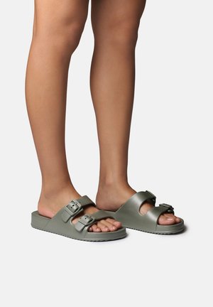 Rohelised libisevad sandaalid kahe reguleeritava pandlaga, lamedal tallal ja siledal, tekstureeritud pinnal, mis esitleb lihtsat ja funktsionaalset disaini.