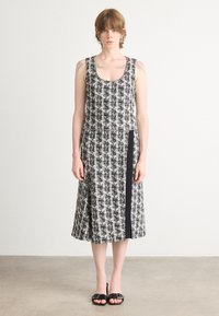 Musta-valkoinen kuviollinen hihaton mekko, jossa on pyöreä kaula-aukko, A-linjainen malli ja sivussa musta korostuspaneeli. Sulava kankaan tekstuuri.