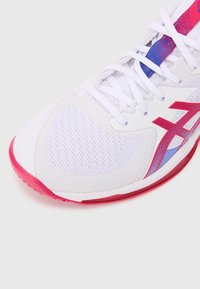 White athletic shoe with breathable mesh upper, striking pink and purple accents, textured sides, and a cushioned sole in pink.