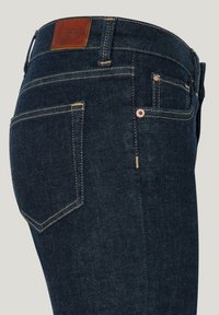 Sötét farmernadrág, slim fit szabással, barna bőr logóval, arany varrással és két hátsó zsebbel, kontrasztos varrással.