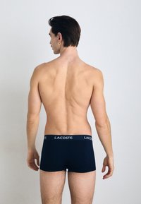 Lacoste navy blue boxer shorts made of soft fabric, featuring a branded elastic waistband and a fitted design, viewed from the back.