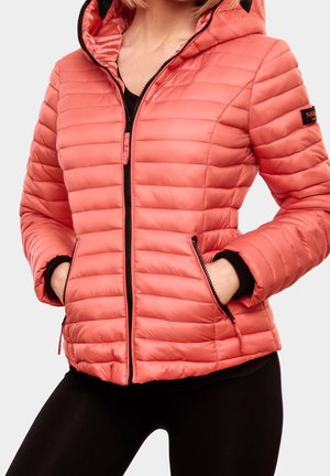 Vrouw draagt een koraalrode doorgestikte donsjas met capuchon, ritssluiting aan de voorkant en zakken, gecombineerd met zwarte legging.