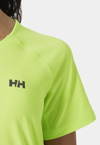Jasně limetkově zelené sportovní tričko s texturovaným žebrovaným vzorem, krátkými rukávy a černým logem na levé přední straně.