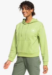 Hoodie verde chiaro con tasca frontale, cappuccio con cordino e polsini a costine. Presenta un piccolo logo bianco sul petto. Tessuto morbido.