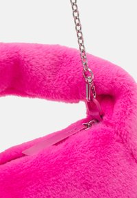 Rosa fuskpälshandväska med en mjuk, fluffig textur; har ett glänsande silverfärgat kedjesnäck och en rosa lädertag som en utmärkande detalj.
