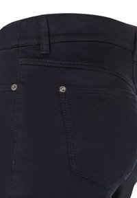 Jean en denim bleu foncé avec une texture lisse, présentant des coutures contrastées, deux poches arrière et des détails en rivets métalliques près des poches.