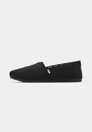 Bottes noires en tissu, à enfiler, avec un bout arrondi, une semelle en caoutchouc et une petite étiquette logo sur le côté. Surface lisse et simple avec un design plat.