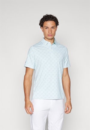 Chemise bleu clair à manches courtes avec un motif géométrique, dotée d'un col et en tissu doux. Portée avec un pantalon blanc.