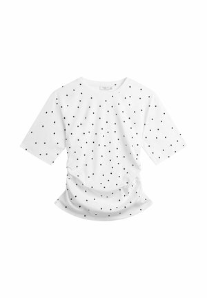 Valkoinen lyhythihainen paita, jossa mustia pilkkuja ja hieman kerätty alareuna, asetettuna tasaisesti valkoiselle taustalle.