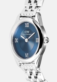 Silver stainless steel watch featuring a round, blue textured dial with Roman numerals and a polished bezel. Attached metal bracelet design.