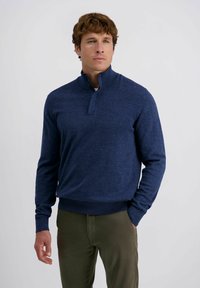 Navyblauer Pullover mit einem Viertelreißverschluss-Kragen, gestrickter Textur, gerippten Bündchen und Saum, kombiniert mit olivgrünen Slim-Fit-Hosen.