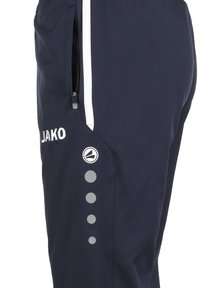 Marine sportbroeken met een ritssluiting zak, witte zijstrepen, logo op het bovenbeen en decoratieve stippenpatronen langs de zijkant.
