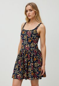 Abito floreale navy con scollatura quadrata, spalline spesse, corpetto aderente e gonna svasata; presenta motivi floreali colorati in rosso, arancione e giallo.