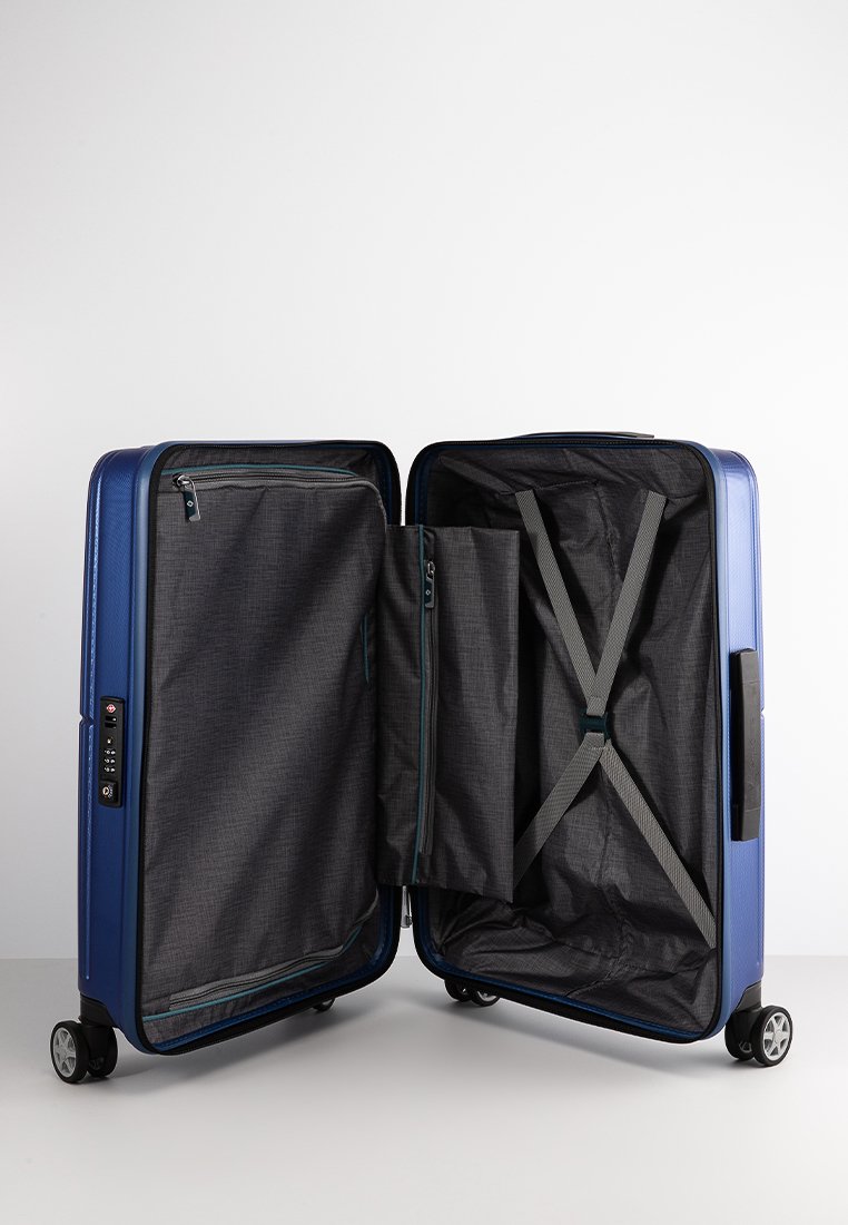 Maleta rígida de color azul oscuro con compartimentos con cremallera, forro de tela gris, correas cruzadas y un candado de combinación en el lateral.