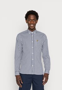 Camisa de cuadros de manga larga en azul marino y blanco, con cuello abotonado y un pequeño logo amarillo en el bolsillo del pecho.