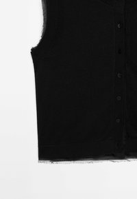 Gilet noir sans manches à boutons avec bords effilochés le long des emmanchures et de l'ourlet sur fond blanc.