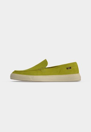 Chaussure basse en daim vert chartreuse à enfiler, avec semelle en caoutchouc blanche texturée et petite étiquette en tissu multicolore sur le côté.