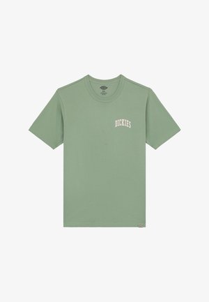 Hellgrünes Baumwoll-T-Shirt mit Rundhalsausschnitt und kurzen Ärmeln. Verfügt über ein weißes "DICKIES"-Logo auf der linken Brust. Schlichtes Design.