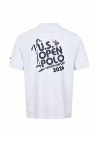 Polo blanc avec texte noir "U.S. Open Polo Championship 2026", deux maillets de polo et un graphisme de joueur de polo dans le dos.
