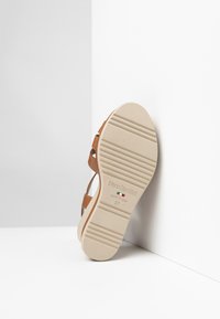 Sandal beige con suola testurizzata marrone, dotata di cinturini regolabili e contrassegnata con "NeroGiardini" e taglia 37. Progettata per il comfort.