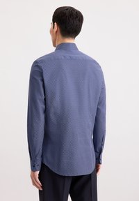 Camicia blu navy con motivo a pois bianchi, maniche lunghe e orlo curvo. Realizzata in tessuto morbido con una vestibilità modellata.