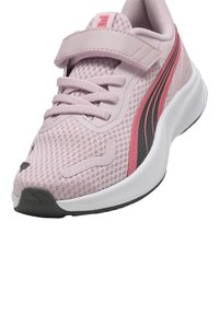 Zapatilla deportiva rosa con parte superior de malla transpirable, que presenta rayas en rosa y negro en contraste, una correa de velcro y una suela de goma blanca.