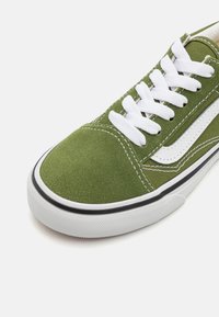 Låg i toppen grön mocka och kanvas sneakers med vita snören, vit sidstripe och vit gummisul med svart trim.