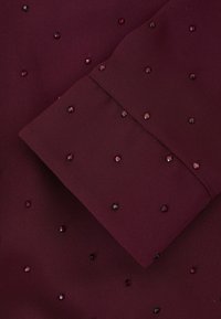 Burgunderfarbener Stoff mit glatter Textur, der über die Oberfläche verstreute dunkle rote und rosa Juwelenverzierungen aufweist.