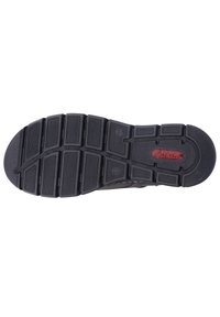 Semelle de chaussure en caoutchouc noir avec un profond motif de sculpture, comportant des rainures horizontales et verticales pour l'adhérence. Finition texturée avec le logo de la marque.