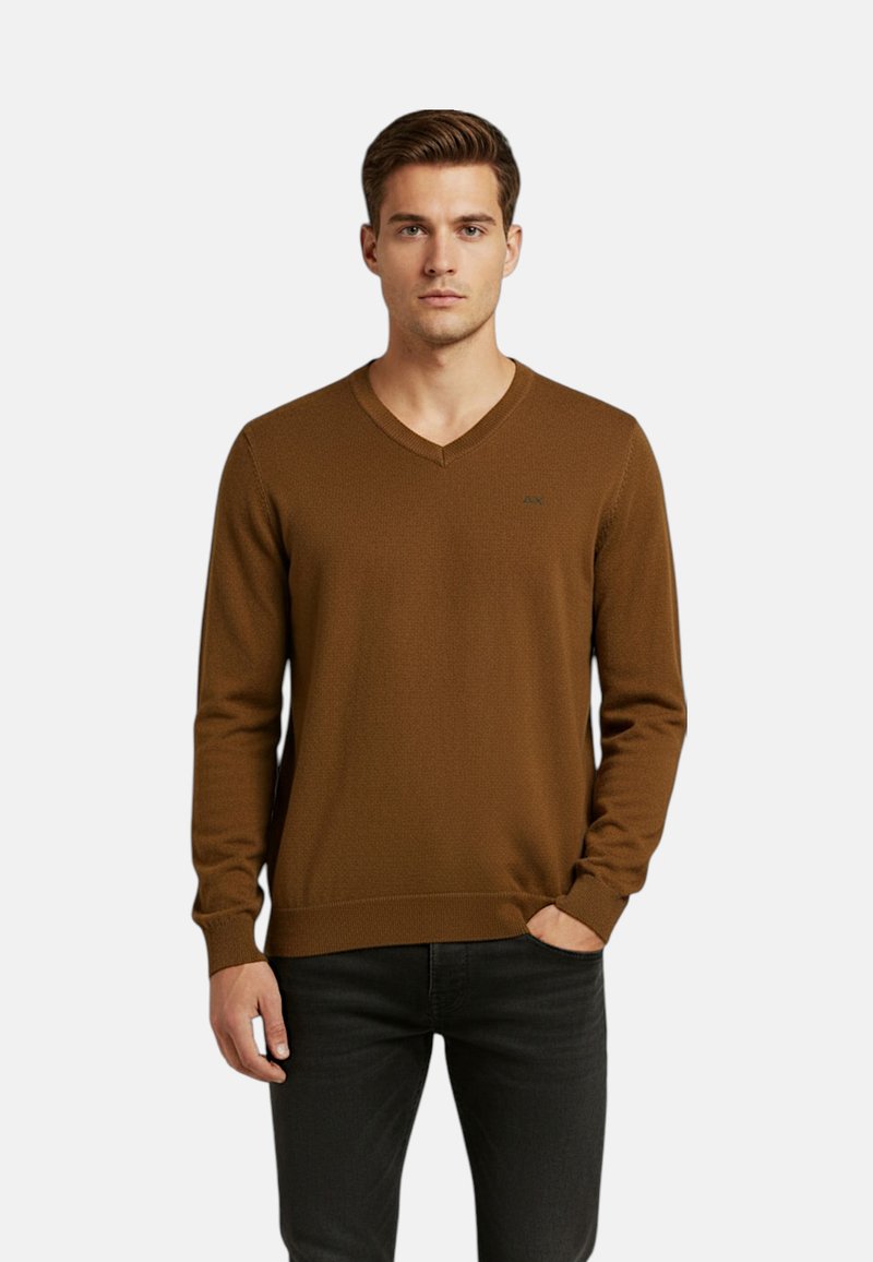 Maglione marrone a maglia con scollo a V, caratterizzato da una texture sottile e un logo sul petto a sinistra, abbinato a jeans neri.