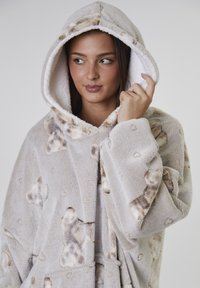 Hooded fleecekappa i ljusgrått med teddybjörnsmönster. Har en mjuk textur och lös passform, med en ficka fram och ett knytbälte.
