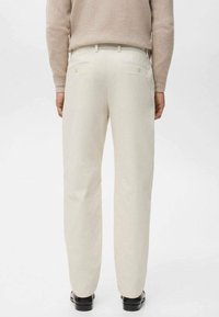 Pantalones de pana color crema con diseño de pierna recta, que cuentan con dos bolsillos traseros y una textura acanalada sutil. Combinados con un suéter ligero.