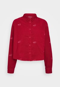 Red corduroy cropped shirt with a collar, button front, and long sleeves; features white logo embroidery throughout and a chest pocket.