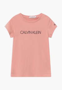 Różowy bawełniany t-shirt z okrągłym dekoltem, krótkimi rękawami oraz czarnym logo "CALVIN KLEIN" nadrukowanym z przodu i małym logo na rękawie.