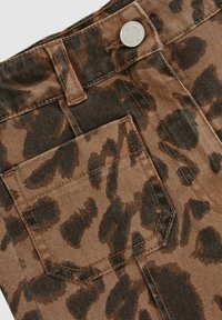 Hnedá denimová látka s leopardím vzorom, so predným vreckom a strieborným gombíkom na páse. Textúrovaný povrch.