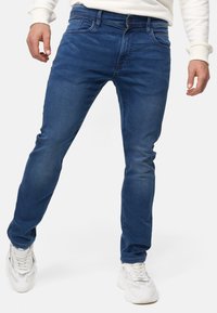 Blå denimjeans med smal passform, med klassisk knapp- og glidelåslukking, femlomme-design og subtile falmingsdetaljer.