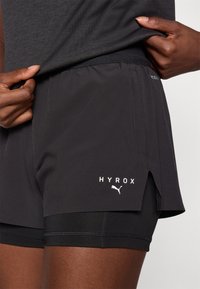 Mustad mustad spordilühikesed püksid, millel on mugav lõige, külgmine lõhe, valge 'HYROX' logo ja Puma embleem sääreosal. Valmistatud kergest materjalist.
