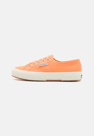 Orange canvas sneaker with white rubber sole, round toe, and lace-up design. Features brand tag on side and textured fabric.