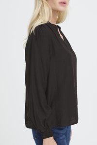 Blusa nera a maniche lunghe con vestibilità rilassata, dettaglio plissettato sulle spalle e piccola apertura a goccia sul collo. Polsini elasticizzati rifiniscono le maniche.