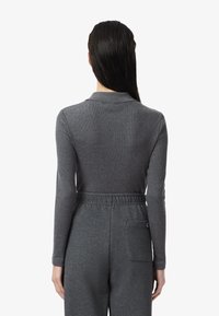 Polo gris à manches longues avec une texture côtelée et un col, associé à un pantalon de jogging assorti avec une taille élastique et une poche arrière.