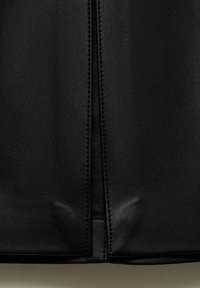 Sac en cuir noir avec une finition texturée, couture centrale et surpiqûres contrastantes le long de la fermeture éclair. Base plate pour plus de stabilité.